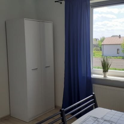 Szafa i okno z widokiem na zabudowania w Kątach